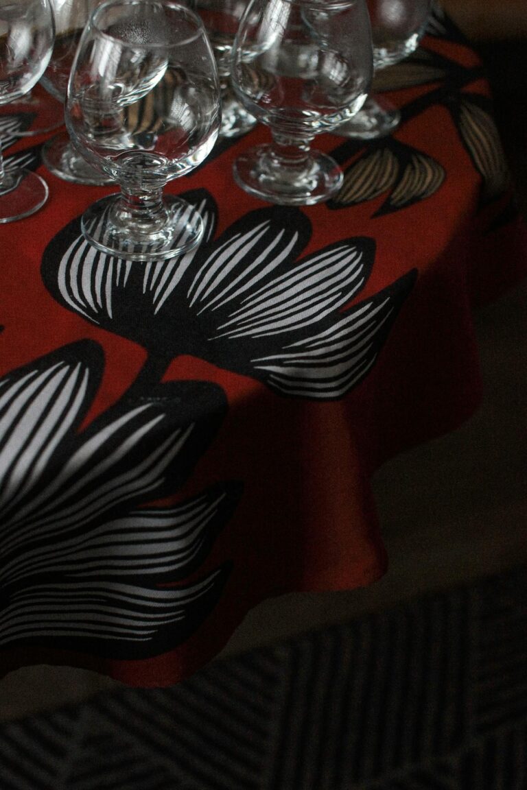 Brandy glasses elegantly placed on a bold floral tablecloth, perfect for dining settings.